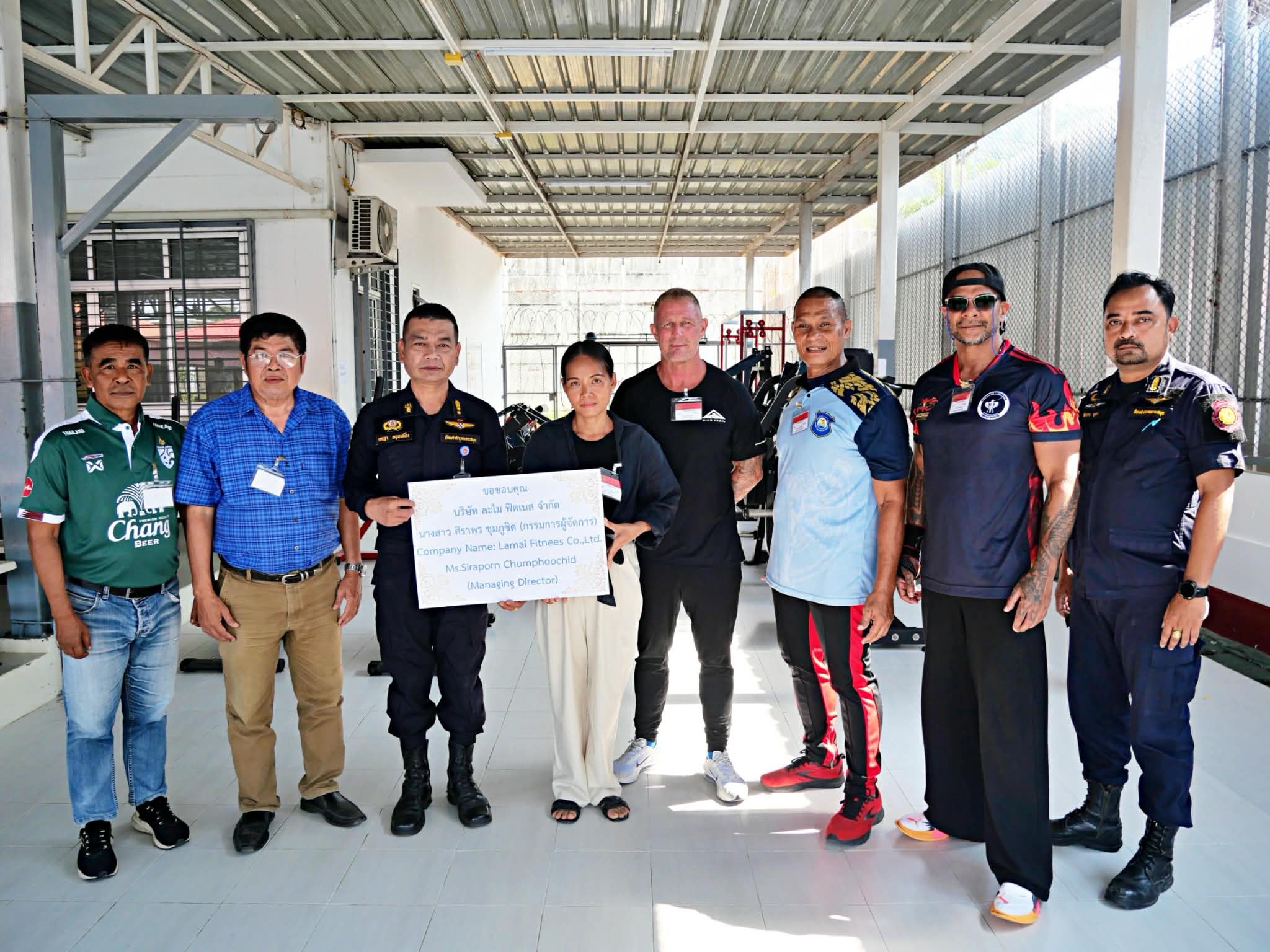 Prison staff and Lamai Fitness Retreat representatives with a thank-you sign in the new gym